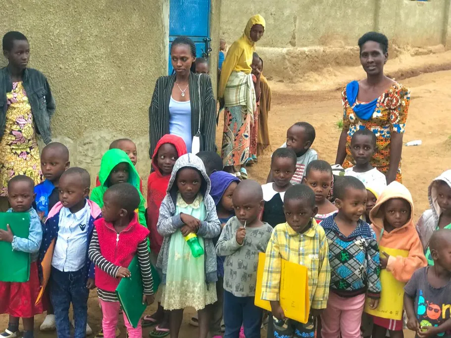 Young children gathered outdoors with several adult caregivers