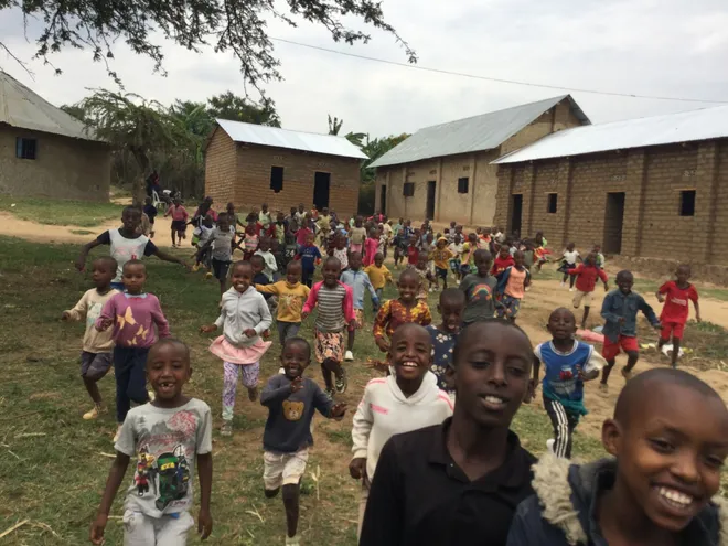 Children running toward the camera between school buildings